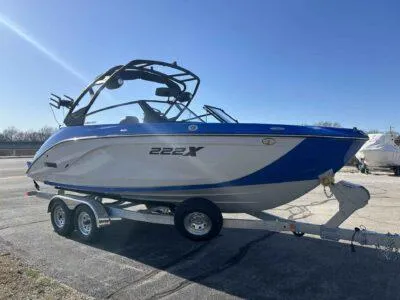 Slide: The Image of 2025 Yamaha Boats 222XE on trailer, blue and white design, parked outdoors. - 2