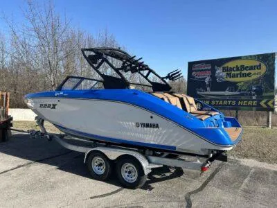 Slide: The Image of 2025 Yamaha Boats 222XE on trailer, blue and white design, parked near BlackBeard Marine sign. - 3
