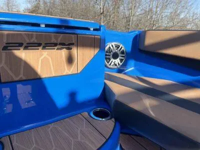 Slide: The Image of 2025 Yamaha Boats 222XE interior with blue and brown seating, speaker, and cup holder. - 7