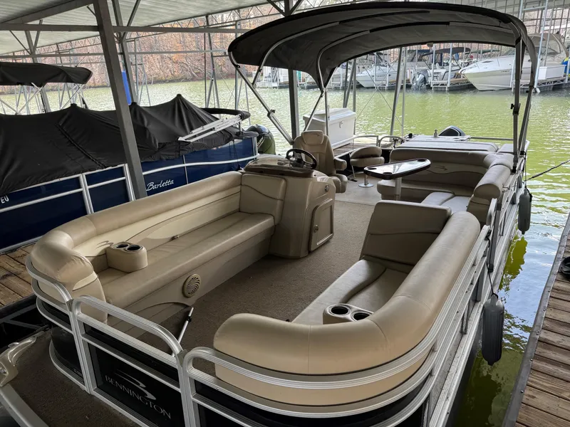 Slide: The Image of 2014 Bennington 22 SSX pontoon boat with beige seating, docked under a covered marina. - 1