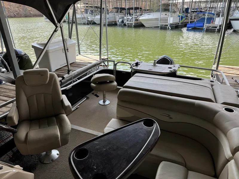 Slide: The Image of 2014 Bennington 22 SSX pontoon boat interior with seating and table, docked by a marina. - 9