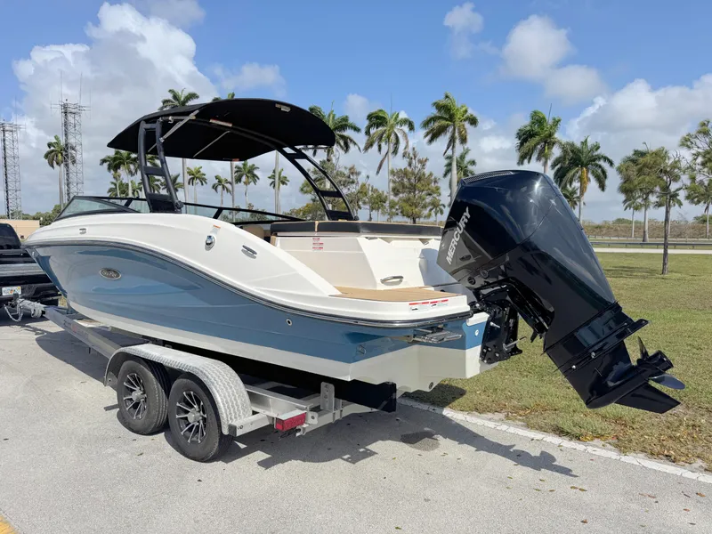 Slide: The Image of 2022 Sea Ray SPX 230 OB boat on trailer, parked outdoors with palm trees in background. - 2
