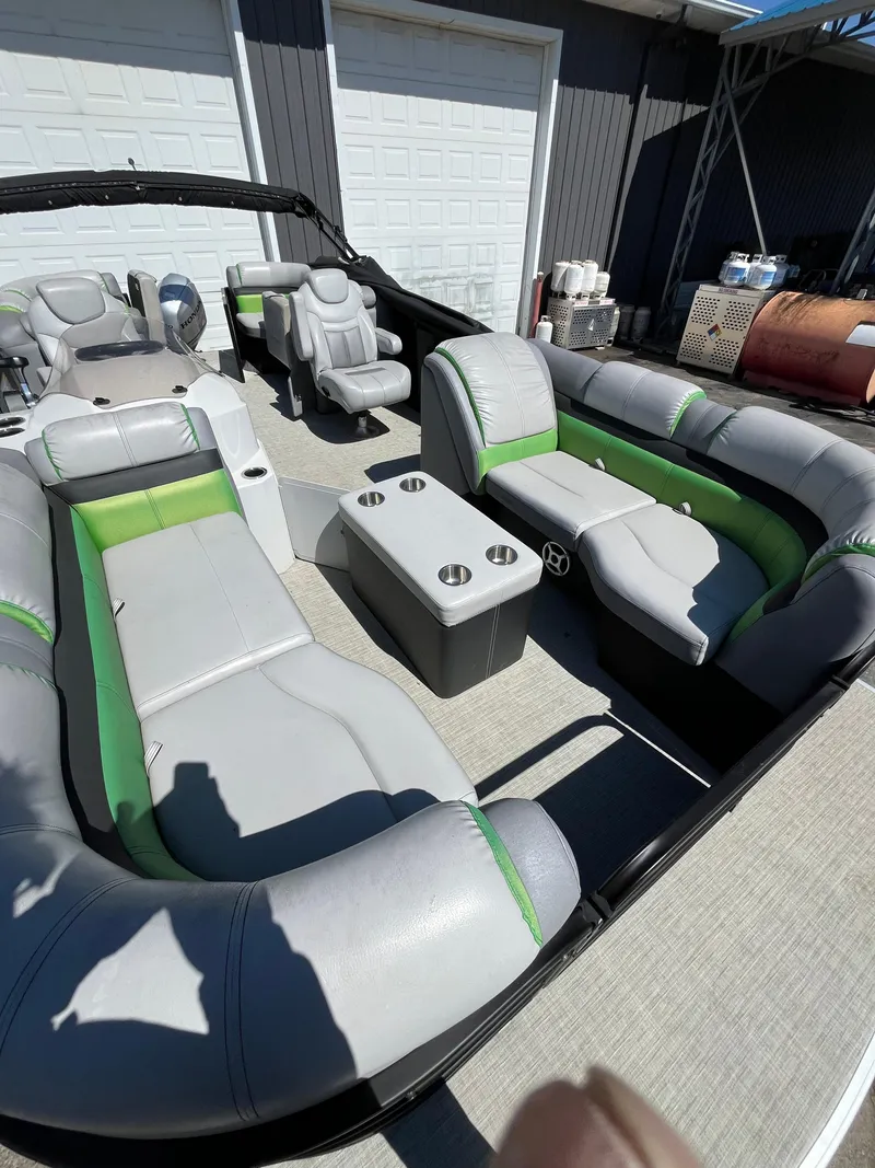 Slide: The Image of 2018 Sweetwater 2286 pontoon boat with gray and green seating, docked near a garage. - 2