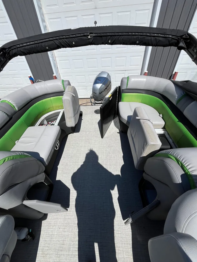 Slide: The Image of 2018 Sweetwater 2286 pontoon boat interior with green and gray seating, shadow visible. - 4