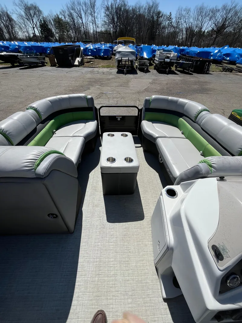 Slide: The Image of 2018 Sweetwater 2286 pontoon boat interior with gray and green seating, cup holders, and console. - 6
