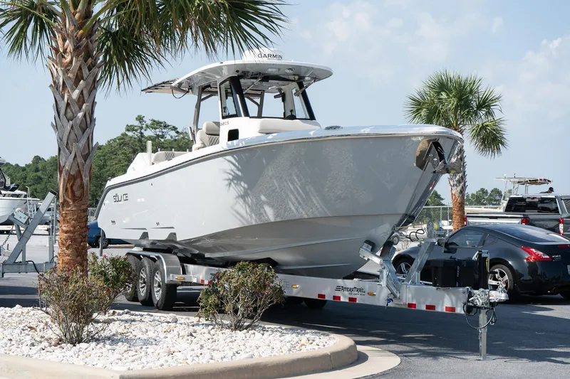 Slide: The Image of 2025 Solace 32 CS boat on trailer, parked near palm trees in a sunny setting. - 13