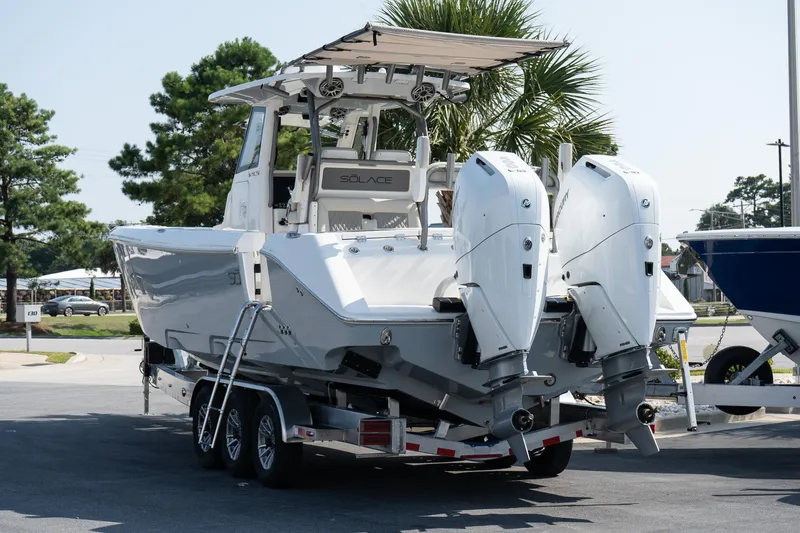 Slide: The Image of 2025 Solace 32 CS boat on trailer with dual outboard engines, parked outdoors. - 14