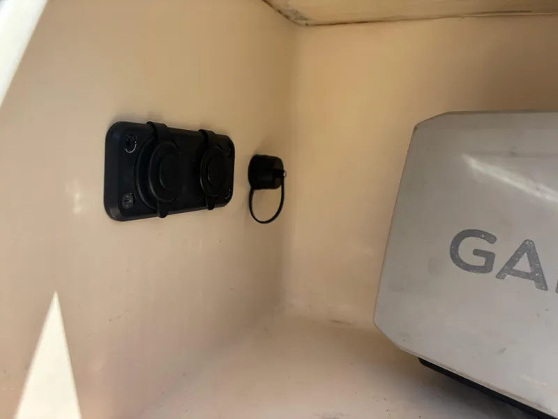 Slide: The Image of 2022 Scout 175 Sportfish boat compartment with Garmin device and electrical outlets. - 15