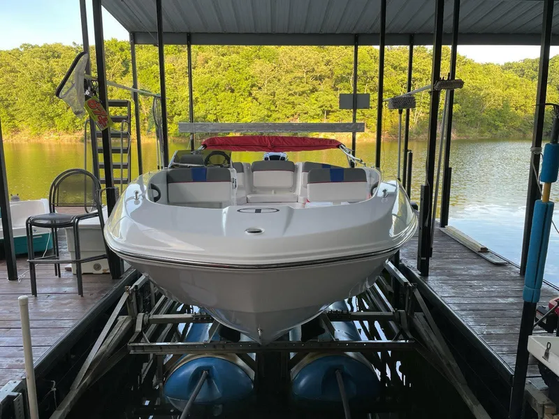 Slide: The Image of 2024 Tahoe T18 boat docked on a lake with lush green trees. - 1