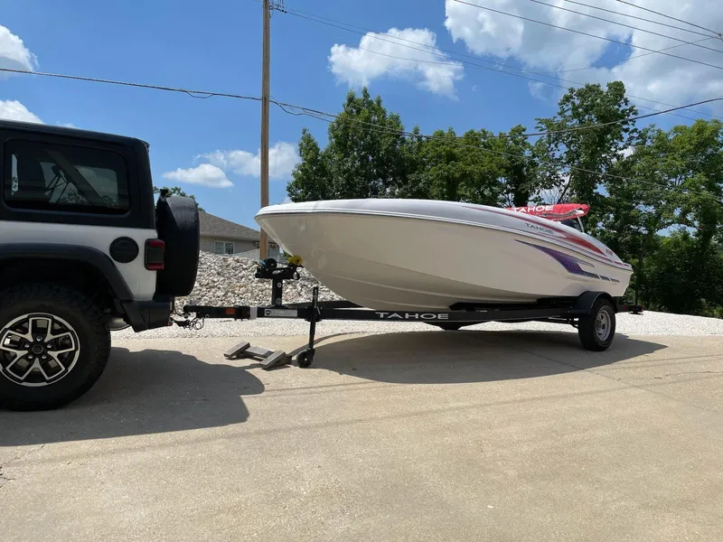 Slide: The Image of 2024 Tahoe T18 boat on trailer hitched to a vehicle, outdoors on a sunny day. - 5