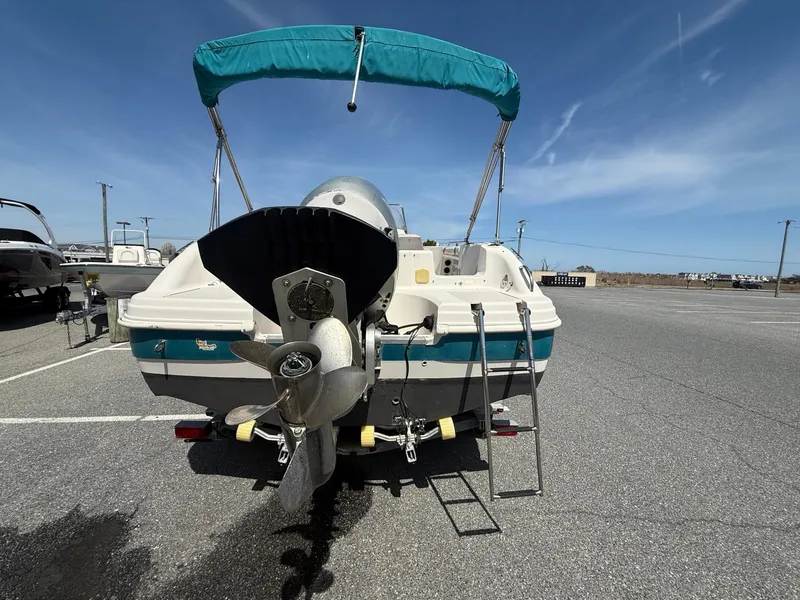 Slide: The Image of 2002 Hurricane Fun Deck GS211 boat with teal canopy and outboard motor in parking lot. - 11