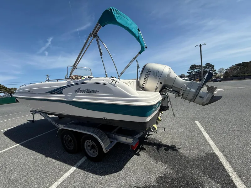 Slide: The Image of 2002 Hurricane Fun Deck GS211 boat on trailer with outboard motor in parking lot. - 4