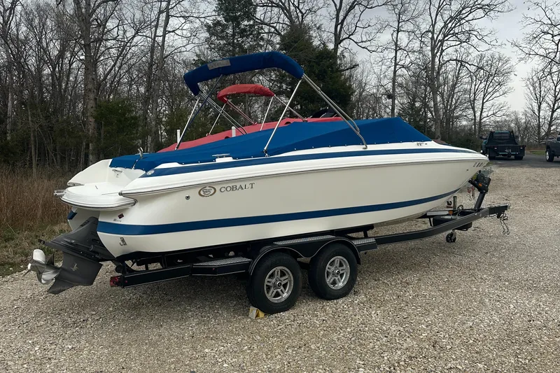 Slide: The Image of 2002 Cobalt 246 boat on trailer, blue and white design, parked outdoors. - 2