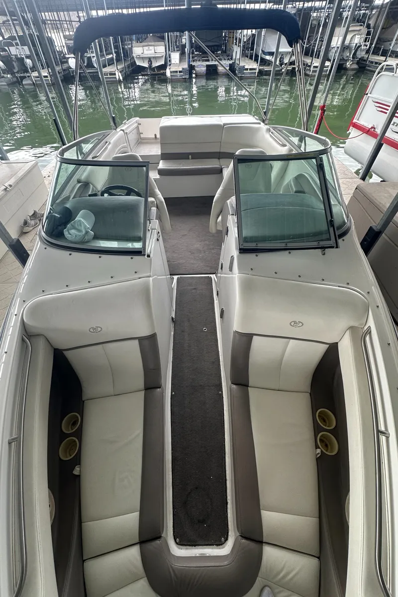 Slide: The Image of 2002 Cobalt 246 boat interior with spacious seating and dual windshields in a marina setting. - 20