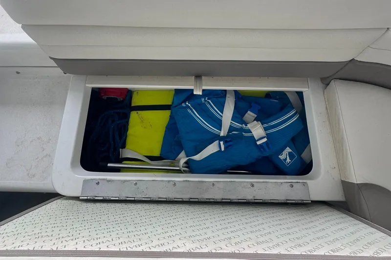 Slide: The Image of Storage compartment in a 2002 Cobalt 246 boat with life jacket and equipment. - 25