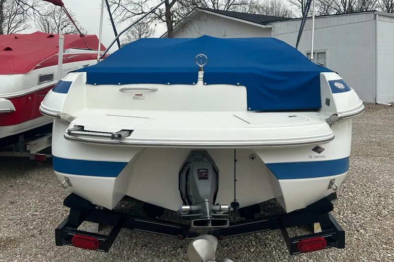 Slide: The Image of 2002 Cobalt 246 boat with blue cover, parked on a trailer in a gravel lot. - 3