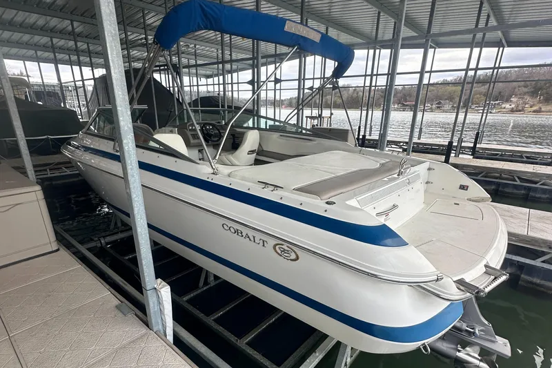 Slide: The Image of 2002 Cobalt 246 boat with blue canopy docked in a covered marina. - 8