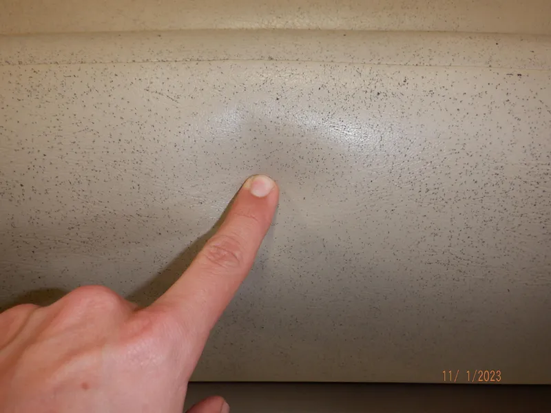 Slide: The Image of Finger pointing at dent on Sylvan Signature 8523 LZ, 2013 model, beige surface. - 22