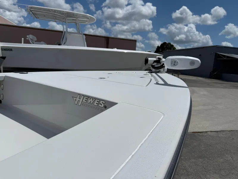 Slide: The Image of 2023 Hewes 18 Redfisher boat, sleek design, parked outdoors under a cloudy sky. - 4