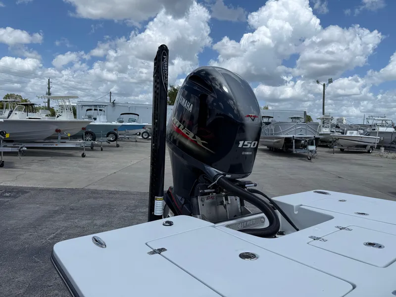 Slide: The Image of 2023 Hewes 18 Redfisher boat with Yamaha 150 engine, parked under a cloudy sky. - 6