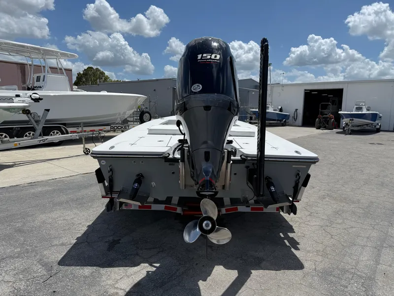 Slide: The Image of 2023 Hewes 18 Redfisher boat with 150 HP engine, parked outdoors under a cloudy sky. - 9