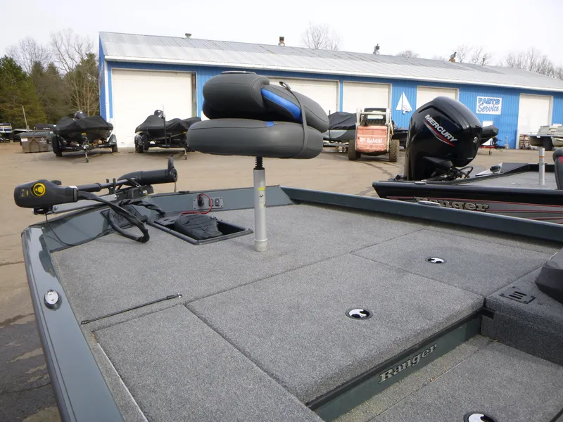 Slide: The Image of 2024 Ranger RT178 boat with fishing seat and motor, parked near blue storage units. - 9