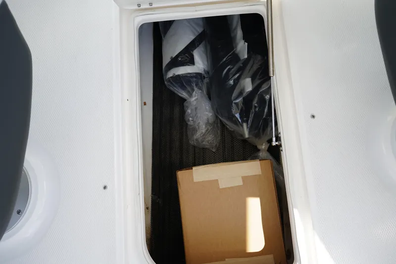 Slide: The Image of Storage compartment in 2025 Chaparral 270 OSX boat with packaged items and a cardboard box. - 13