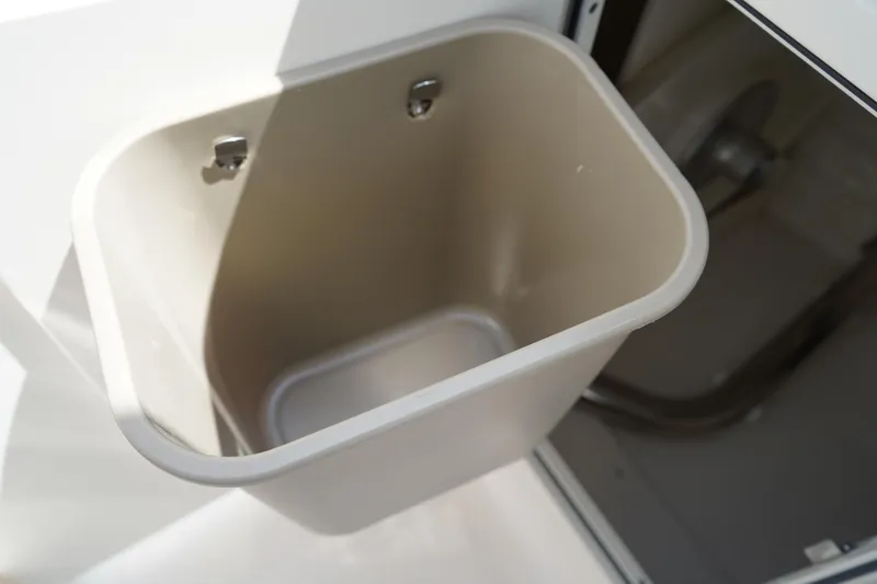 Slide: The Image of Storage compartment in 2025 Chaparral 270 OSX boat, featuring a built-in waste bin. - 32