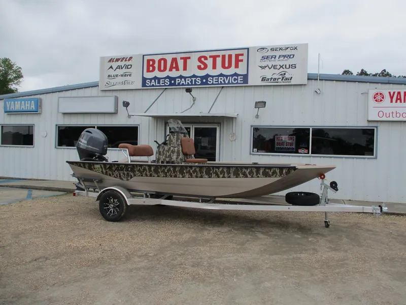 Slide: The Image of 2025 Avid 18 Rogue CC boat on trailer outside dealership, featuring camouflage design. - 0
