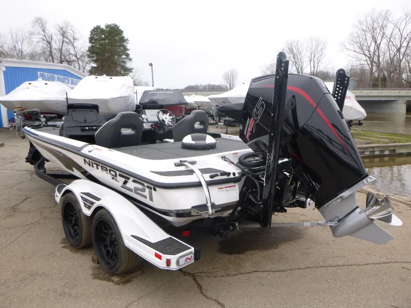 Slide: The Image of 2025 Nitro Z21 XL Pro boat with powerful engine, parked on a trailer near a marina. - 2