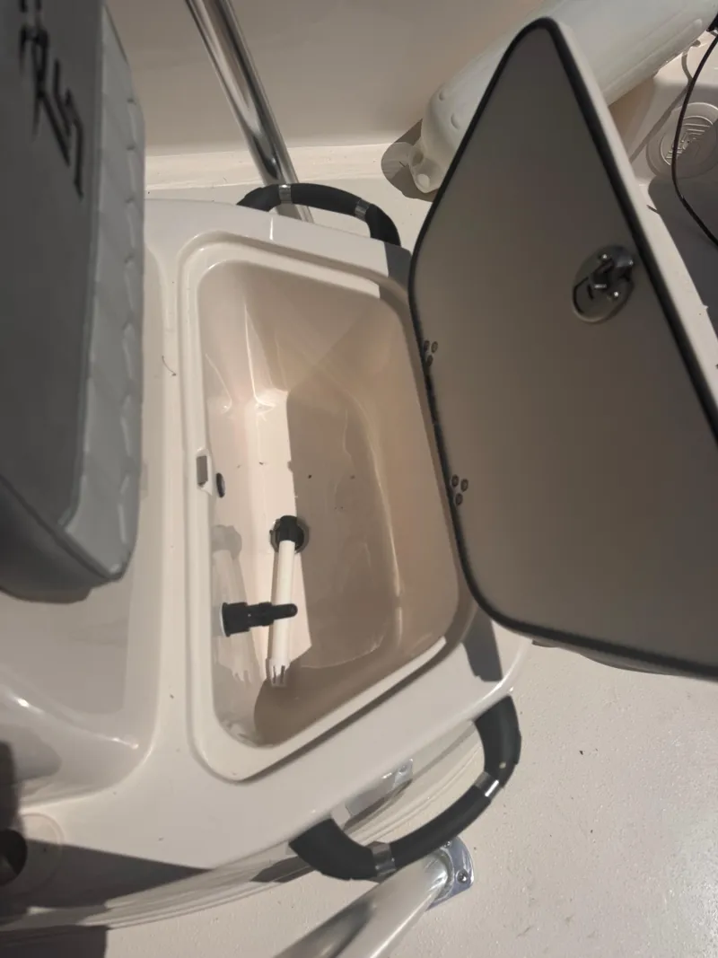 Slide: The Image of 2024 Carolina Skiff 21 LS boat storage compartment with open lid and interior view. - 9