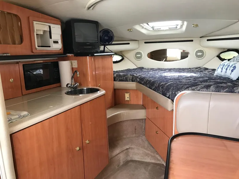 Slide: The Image of 1999 Regal 292 Commodore cabin interior with kitchenette, bed, and seating area. - 11