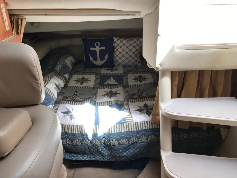 Slide: The Image of 1999 Regal 292 Commodore cabin with nautical-themed bedding and anchor pillow. - 13