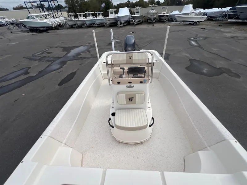 Slide: The Image of 2019 Carolina Skiff 218 DLV boat interior with console and seating, parked in a marina. - 14