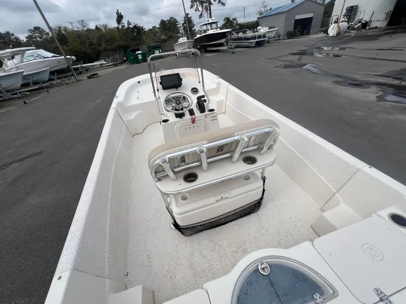 Slide: The Image of 2019 Carolina Skiff 218 DLV boat interior with console and seating, parked outdoors. - 15