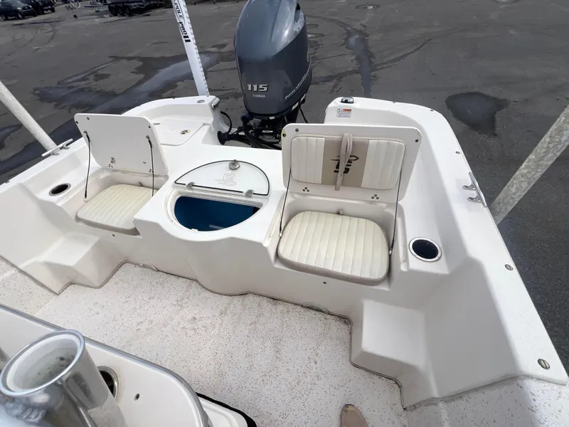 Slide: The Image of 2019 Carolina Skiff 218 DLV boat with seating and motor, docked on a concrete surface. - 7