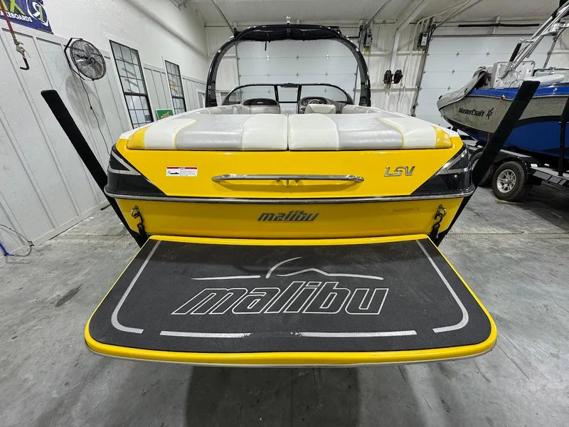 Slide: The Image of 2007 Malibu Sunscape 23 LSV boat in a garage, rear view with yellow detailing. - 2