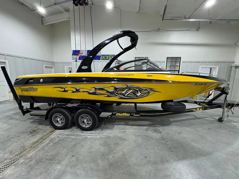 Slide: The Image of 2007 Malibu Sunscape 23 LSV boat, yellow with black graphics, on a trailer in a garage. - 3