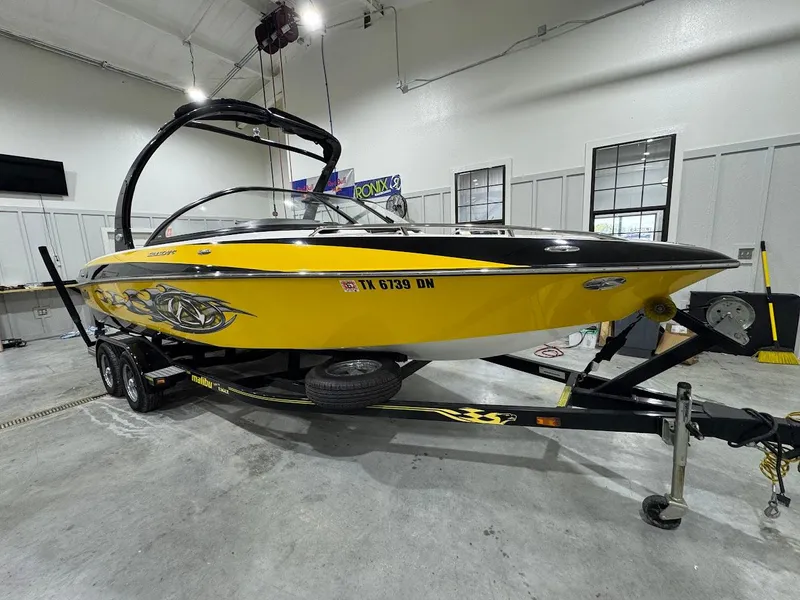 Slide: The Image of 2007 Malibu Sunscape 23 LSV boat in a garage, yellow with custom graphics. - 4