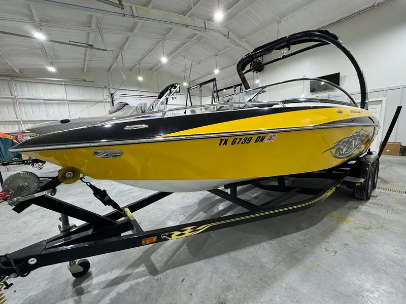 Slide: The Image of 2007 Malibu Sunscape 23 LSV boat in a garage, yellow and black design on trailer. - 5