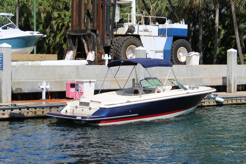 Slide: The Image of 2022 Chris-Craft Launch 27 boat docked at marina with canopy and American flag. - 27