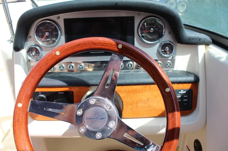 Slide: The Image of 2022 Chris-Craft Launch 27 dashboard with wooden steering wheel and classic gauges. - 6