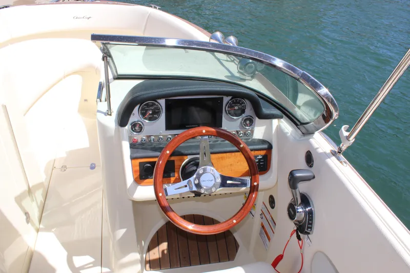 Slide: The Image of 2022 Chris-Craft Launch 27 dashboard with wooden steering wheel and modern controls. - 7