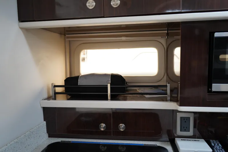 Slide: The Image of Interior of 2016 Sea Ray 330 Sundancer with dark wood cabinetry and window. - 39