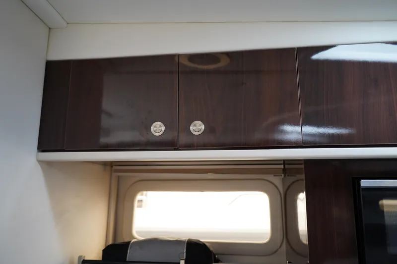 Slide: The Image of 2016 Sea Ray 330 Sundancer interior with sleek wooden cabinets and window. - 40