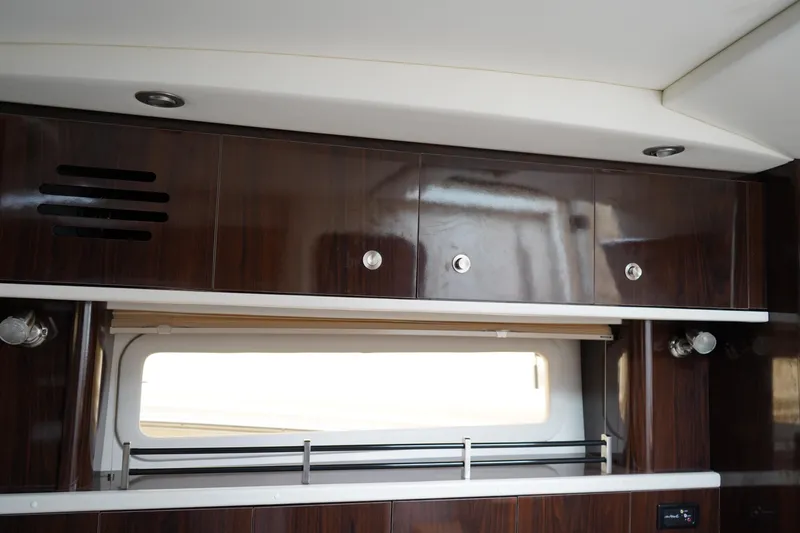 Slide: The Image of Interior view of 2016 Sea Ray 330 Sundancer with sleek wooden cabinets and window. - 45