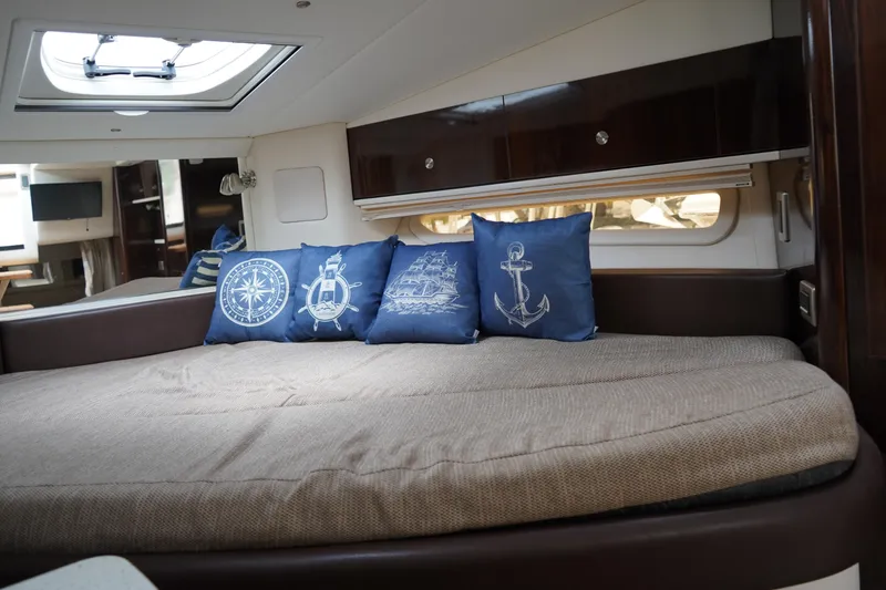 Slide: The Image of Interior of 2016 Sea Ray 330 Sundancer with nautical-themed pillows on a cozy bed. - 46