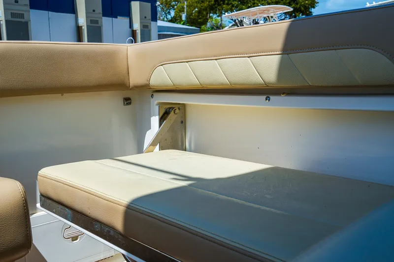 Slide: The Image of 2019 Sailfish 245 DC boat interior with beige seating and storage compartment. - 14
