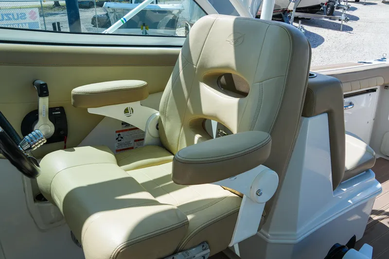 Slide: The Image of 2019 Sailfish 245 DC boat interior with beige captain's chair and control panel. - 19