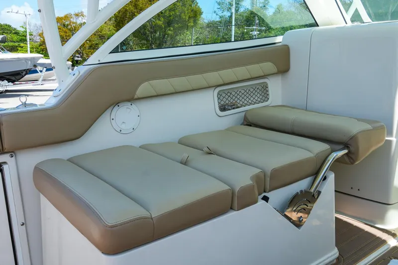 Slide: The Image of 2019 Sailfish 245 DC boat interior with beige cushioned seating and storage compartment. - 28
